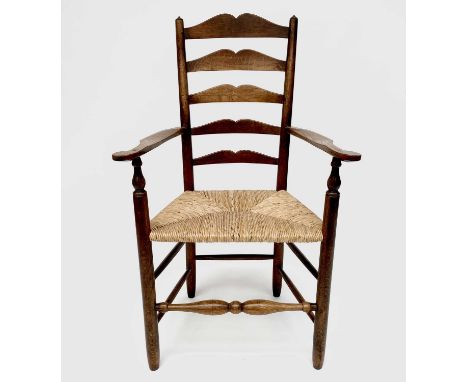 Robin Nance, An Arts and Crafts elbow ladder back elbow chair, with rush seat and turned supports, height 108.5cm.