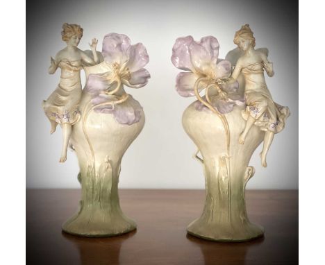 A pair of Austrian Art Nouveau porcelain figural vases, moulded with seated females beside lilies and dragonflies, height 32c