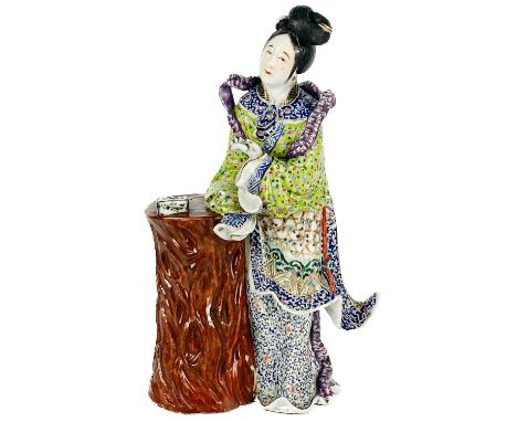 A Chinese porcelain figure of a lady leaning on a tree stump.  Height 29.5cm, width 17cm, depth 9cm.An item has been lost fro