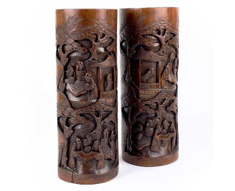 A pair of Chinese bamboo cylindrical brush pots, circa 1900. Carved with temples, trees and figures playing board games or ma