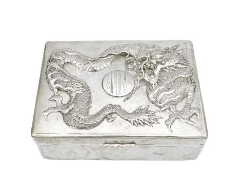 A Chinese sterling silver cigar box, circa 1900. The hinged cover decorated in high relief with a dragon chasing an initialle