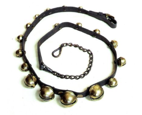 A FINE RING OF EIGHTEEN BRASS RUMBLER BELLS ON A MARTINGALE. The bells may predate the 19th century brass symbols that stud p