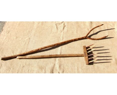 A WOODEN PITCH FORK AND A WOODEN SWATHE GATHERING RAKE. Both 19th century. The rake bears two inscribed sets of initials. The