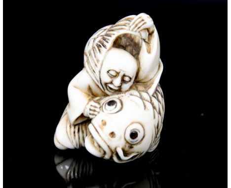 An oriental ivory netsuke, carved as a man restraining a large carp. signed, height 5cm