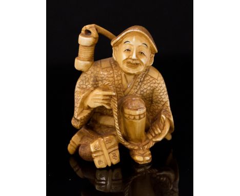 An Oriental ivory netsuke, carved as a seated man with rope, signed, height 5cm