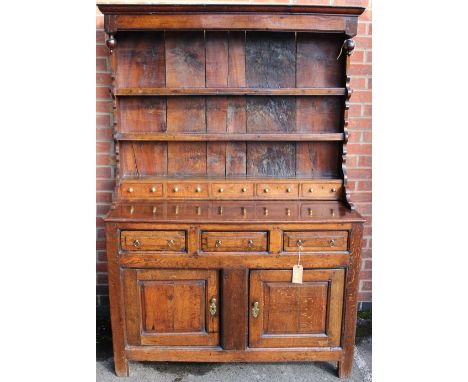 A George III oak dresser and rack, the rack with three shelves and five spice drawers, the base section with three drawers ov