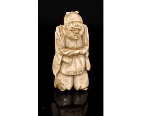 An oriental bone netsuke, carved as a man standing in traditional dress, height 5cm