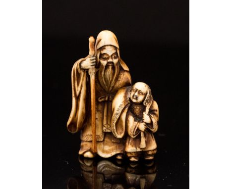 An Oriental ivory netsuke, carved as a bearded elder with staff and a n infant, height 4cm