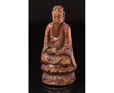 An Oriental treen netsuke, carved as buddah seated upon a lotus leaf, height 6cm