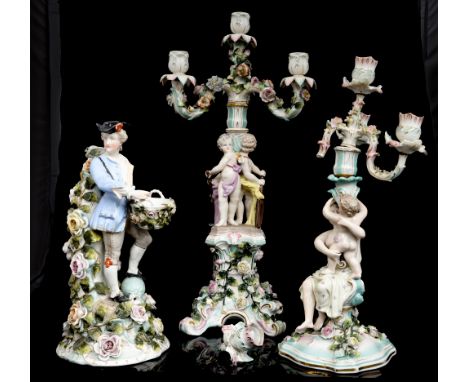 *Three Dresden porcelain figural candlesticks, one modelled as a mother and child, on a florally encrusted Rococo base, anoth