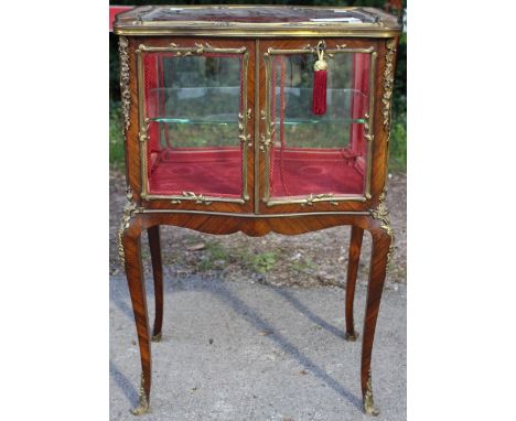 *A 19th Century kingwood and ormolu mounted vitrine, serpentine form, having a glazed top, the two glazed doors enclosing a s