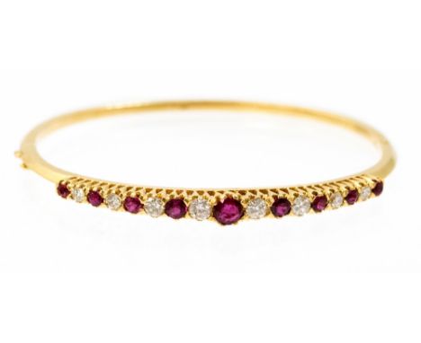 A ruby and diamond set 18ct yellow gold hinged bangle, nine round cut rubies graduating between approximately 4.5mm to 2.5mm 