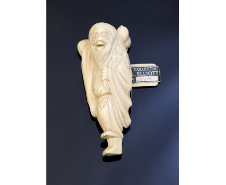 An oriental ivory netsuke, carved as a smiling elderly man standing on one foot holding a gourd, height 6cm, with old label '