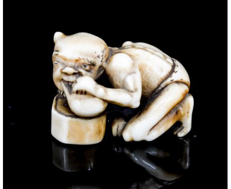 An oriental ivory netsuke, carved as a crouching demon eating a gourd, width 4cm