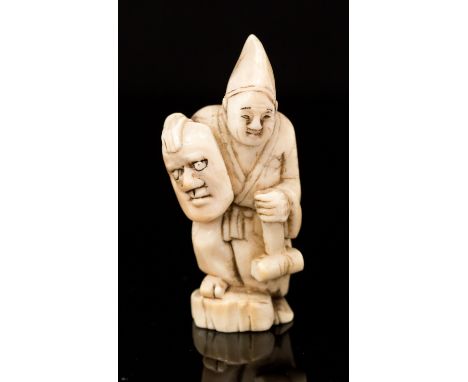 An Oriental ivory netsuke, carved as a man standing wearing a hat, and holding a mallet and a mask, signed, height 4cm