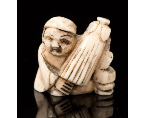 An oriental bone netsuke, carved as a seated man with a parasol, height 2cm