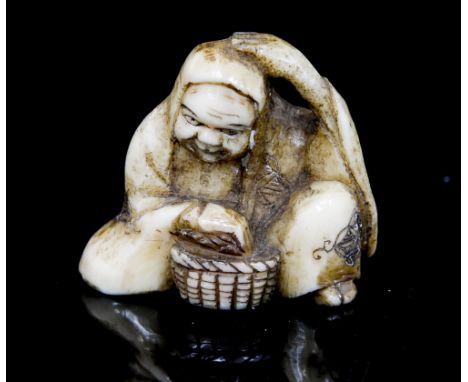 An Oriental bone netsuke, carved as a seated man with a basket, height 3cm
