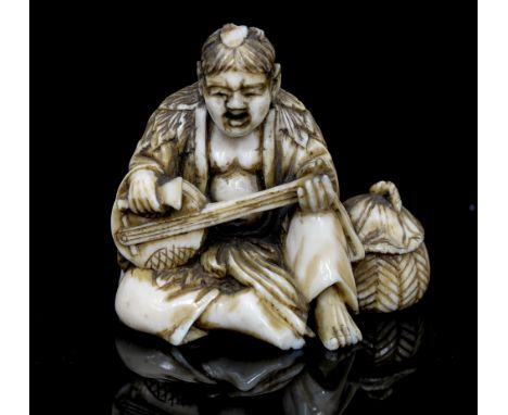 An Oriental ivory netsuke, carved as a seated man playing a string instrument, signed, height 4cm