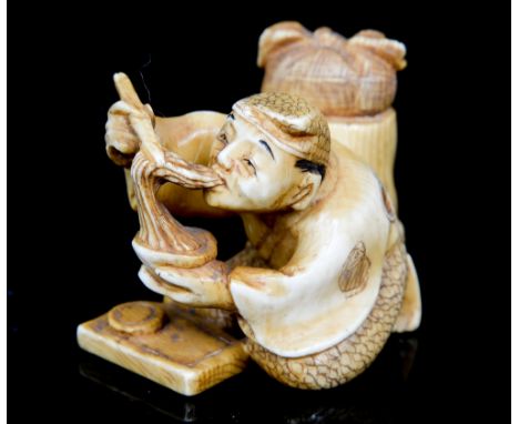 An Oriental ivory netsuke, carved as a man eating with chopsticks, signed, width 5cm