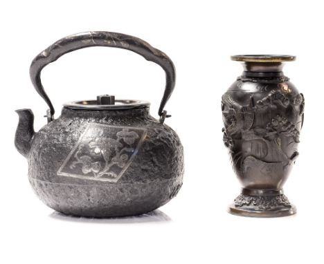 A Japanese Tetsubin, the cast iron kettle body of squat ovoid form, inlaid with silver cartouches and a vine motif to the han