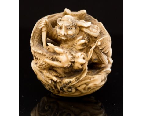 An Oriental ivory netsuke, of ball form carved with a figure slaying a dragon, diameter 5cm