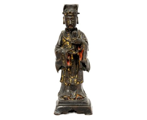 A Chinese bronze figure of a deity, possibly Ming, modelled holding  a scroll, remnants of gilding, 26cm high