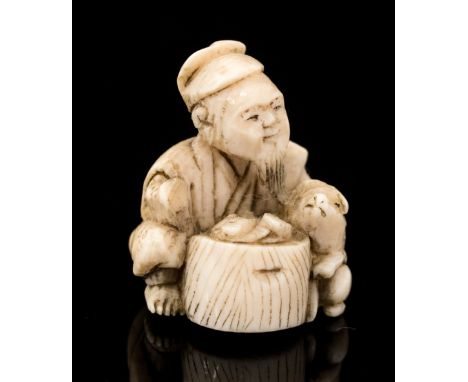 An Oriental ivory netsuke, carved as man and a dog beside a basket, height 2.5cm