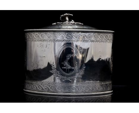 A George III silver oval shaped tea caddy with a lock and working key, the lid having a cast foliate finial and an engraved p