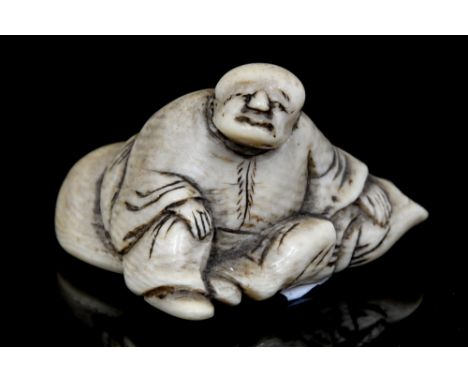 An Oriental ivory netsuke, carved as a man seated upon a rock, width 3.5cm