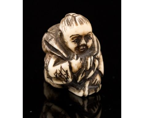 An Oriental bone netsuke, carved as a crouching boy with a backpack, height 2cm