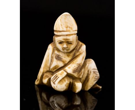 An oriental ivory netsuke, carved as a seated man wearing a hat, height 3.5cm