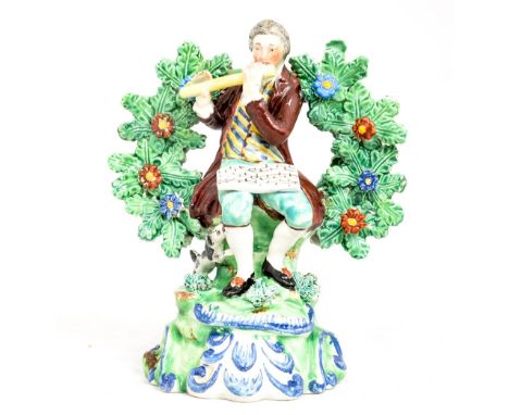 A Staffordshire figure of a musician, seated by a tree playing a pipe with a dog sitting at his side, circa 1820, height 16 c
