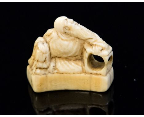 An Oriental ivory netsuke, carved as an old sage on a plinth, width 3.5cm, old label 'Ex Collectis, T.L. Elliott'