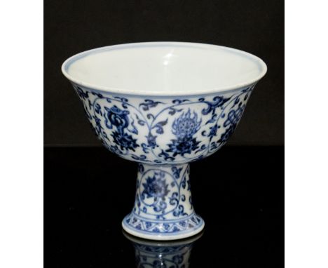 A Chinese blue and white stem cup, Kangxi style, decorated with lotus flowers and scrolling vines, the centre of the bowl wit