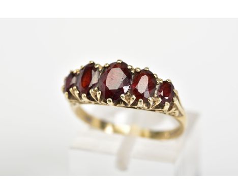 A 9CT GOLD GARNET RING, designed with a row of five graduated oval cut garnets and scrolling gallery, with a 9ct hallmark for