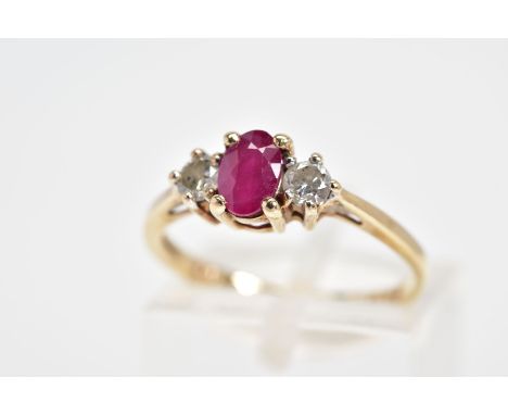 A 9CT GOLD RUBY AND DIAMOND RING, the central oval glass filled ruby flanked by brilliant cut diamonds, all within claw setti