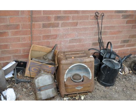 THREE OVER PAINTED VINTAGE WATERING CANS, a vintage heater, three hooked wrought iron bars and two vintage lamp oil bottles w