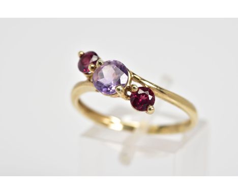 A 9CT GOLD THREE STONE RING, designed as a diagonal row of three stones, the central circular amethyst flanked by circular cu