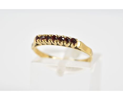 AN 18CT GOLD GARNET RING, designed as a row of circular cut garnets, to the plain polished band, stamped 750, ring size K 1/2