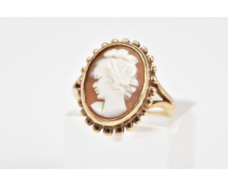 A 9CT GOLD CAMEO RING, of oval design depicting a lady in profile within a collet mount to the scallop surround and bifurcate