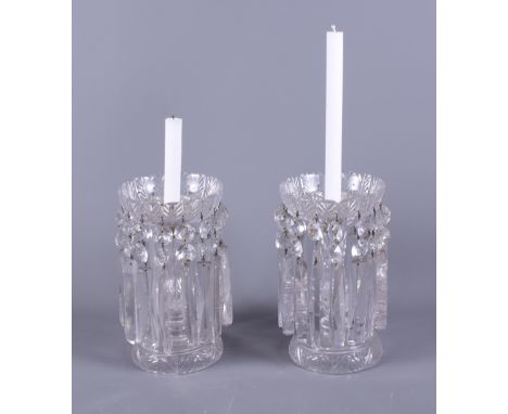 A pair of Edwardian clear glass table candlestick lustres with hanging prism drops, on shaped moulded bases, 10" high