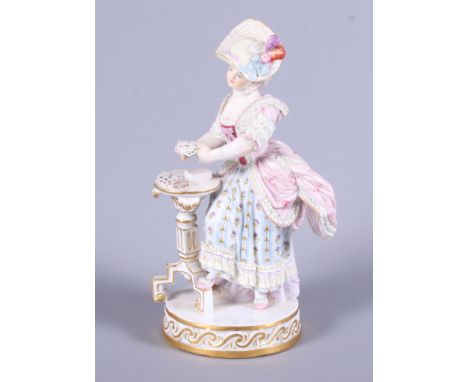 A late 19th century Meissen porcelain figure of a standing woman in 19th century costume by a tripod table playing cards, "Th