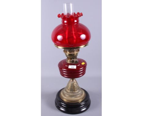 A late Victorian/early 20th century brass and ruby glass oil lamp, 23" high, together with two carriage lamps and two carryin