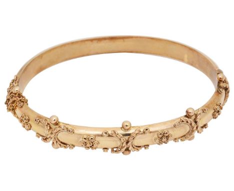 A Victorian 9ct gold stiff banglewith applied decoration of rope twist C scrolls, flowers and spheres, with safety chain, con