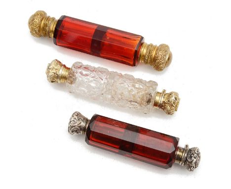 Three Victorian double ended glass scent bottles,comprising a ruby glass bottle mounted with brass hinged lids and internal s