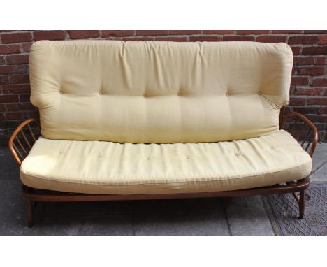 An Ercol three-seater sofa in mid-brown elm finish, with curved stick back, raised on turned supports and with yellow, button