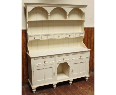 A white painted pine dresser with galleried top and planked back above a shelf, with five drawers beneath, the base with two 