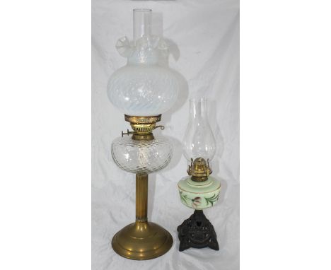 A Victorian brass oil lamp with clear glass reservoir and white shade with ruffled edge, together with another smaller Victor