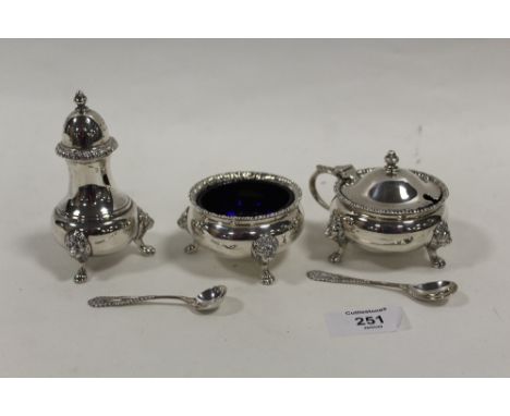 A HEAVY GAUGE HALLMARKED SILVER THREE PIECE CRUET SET WITH LION MASK DETAIL TOGETHER WITH SILVER CONDIMENT SPOONS