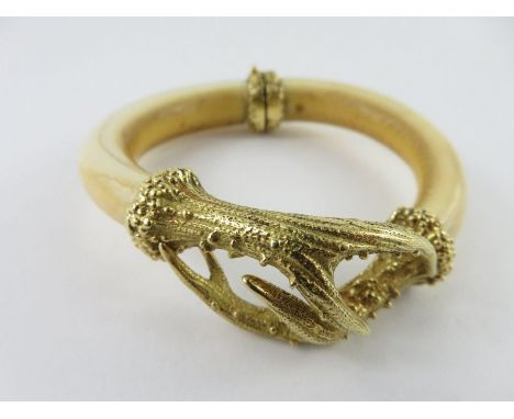 A gold mounted ivory hinged bangle, stamped ‘750’, with cast horn like fittings, inner diameter 5.8cm